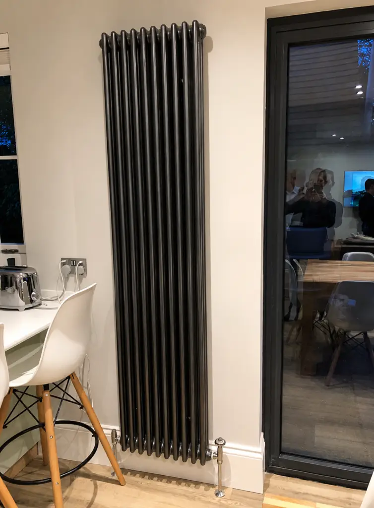 Black vertical designer radiator installed in a modern interior in Valencia.